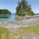2 people stand on shore by the narrow inlet of a lake